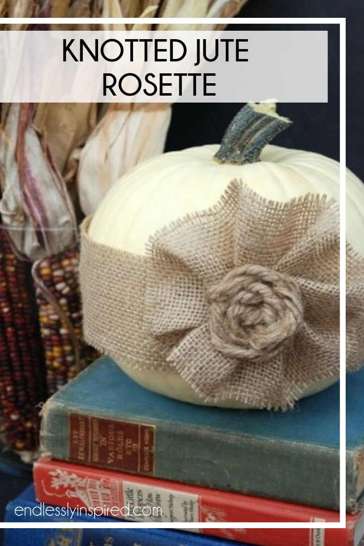 White pumpkin with a burlap ribbon and burlap flower on a stack of books