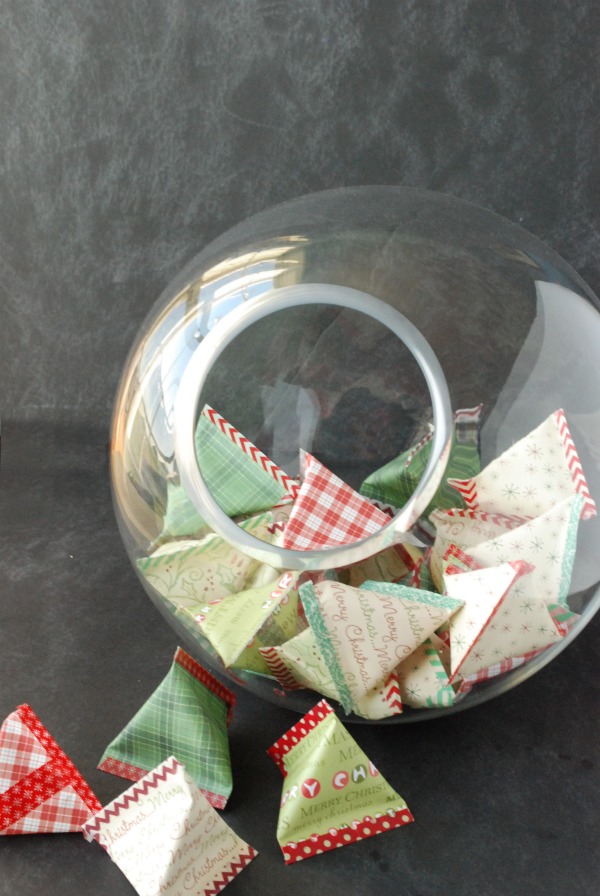 Scrapbook paper pouches in a clear glass bowl and on a table